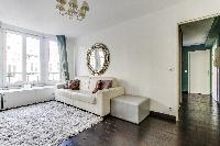 elegant open plan living with white sofa, furry cream carpet rug and gree draped windows in Paris lu