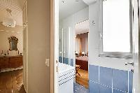 blue-tiled bathroom furnished with a shower area, a sink, a mirror, and a hairdryer with access to t