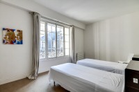 second bedroom with two single beds and a built-in closet in a 2-bedroom Paris luxury apartment