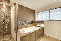 an en-suite bathroom with double sinks, a toilet, a full bathtub, and a shower area with a detachabl