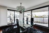 elegant dining area with a glass table and six black chairs and access to the balcony in Paris luxur