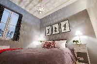 bedroom with built-in cabinets, two bedside tables with lamps, and a double bed 1-bedroom Paris luxu