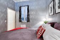 bedroom with built-in cabinets, two bedside tables with lamps, and a double bed 1-bedroom Paris luxu