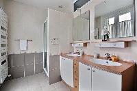 an en-suite bathroom with a sink, a bathroom cabinet, a mirror, and a shower area in a 2-bedroom Par